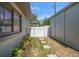 A side yard with a stone walkway, a white fence, and lush plants, creating a charming and inviting outdoor space at 13514 Oval W Dr, Largo, FL 33774