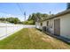 Wide backyard with white fencing offering privacy, a storage shed, and a home exterior with a door and air conditioning unit at 13514 Oval W Dr, Largo, FL 33774