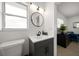 Bathroom features a black vanity, black hardware, a round mirror, and natural light at 13514 Oval W Dr, Largo, FL 33774