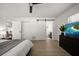 Bedroom featuring a barn door, hardwood floors, ceiling fan, and a TV at 13514 Oval W Dr, Largo, FL 33774