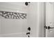 Shower featuring white tiling with mosaic tile accent, and modern matte black showerhead and faucet at 13514 Oval W Dr, Largo, FL 33774