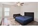 Well-lit bedroom with dark wood flooring, offering a comfortable blue bed and an adjacent lounge area at 146 Rain Berry Ave, Ruskin, FL 33570
