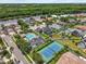 Community aerial view featuring a pool, tennis court, and homes surrounded by lush greenery, creating a serene residential setting at 1622 Lago Vista Blvd, Palm Harbor, FL 34685