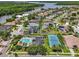 Beautiful aerial view showcasing community pool, tennis court, and nearby waterway, set against lush landscaping and residential homes at 1622 Lago Vista Blvd, Palm Harbor, FL 34685
