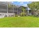 Lush backyard with screened-in patios offers a private oasis for outdoor relaxation and entertaining at 1622 Lago Vista Blvd, Palm Harbor, FL 34685
