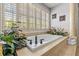 Luxurious bathroom features a soaking tub with tile surround and plantation shutters for bright natural light at 1622 Lago Vista Blvd, Palm Harbor, FL 34685