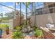 Scenic view of a screened-in patio with lush greenery, rock waterfall feature and comfortable furniture at 1622 Lago Vista Blvd, Palm Harbor, FL 34685