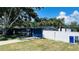 Exterior view of the home with a well-kept lawn, a driveway, a blue garage door, and a white fence at 1631 St Mary Dr, Dunedin, FL 34698