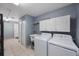 This laundry room has tile floors, white cabinets, and updated washer and dryer at 1706 Sloop Pl, Brandon, FL 33511