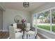 Bright dining area featuring a glass table set, a modern light fixture and a large window with lush backyard views at 2010 Bayview Pl, Indian Rocks Beach, FL 33785
