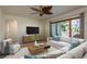 Bright living room featuring a large window, ceiling fan, and comfortable seating arrangement with modern decor at 2010 Bayview Pl, Indian Rocks Beach, FL 33785