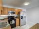 Bright kitchen featuring stainless steel appliances, wood cabinetry, and modern marble-patterned flooring at 21032 Voyager Blvd # 8, Land O Lakes, FL 34638