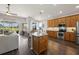 Open kitchen with stainless steel appliances, oak cabinets, granite counters, an island, and hardwood floors at 2350 126Th E Dr, Parrish, FL 34219
