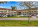 Three-story condo complex featuring parking, palm trees, and manicured landscaping under a blue sky at 2434 Australia E Way # 38, Clearwater, FL 33763
