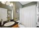 A bathroom with a wood vanity, black countertops, and a shower with white curtain at 2616 11Th N St, St Petersburg, FL 33704