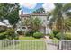 Inviting two-story home with a classic tiled roof, lush landscaping, and a charming white picket fence at 2616 11Th N St, St Petersburg, FL 33704