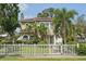 Inviting two-story home with a classic tiled roof, lush landscaping, and a charming white picket fence at 2616 11Th N St, St Petersburg, FL 33704
