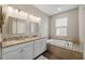 Bright bathroom with dual sinks, granite countertops, and a large soaking tub, offering a luxurious and comfortable retreat at 3091 King Fern Dr, Wimauma, FL 33598