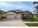 Attractive single Gathering home featuring a well-manicured lawn, stone accents, and a spacious three-car garage at 3091 King Fern Dr, Wimauma, FL 33598