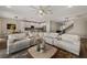 Spacious living room featuring a white sofa set, a modern ceiling fan, and views into the bright kitchen at 3091 King Fern Dr, Wimauma, FL 33598