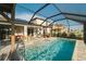 Beautiful screened-in pool with a sun shelf, outdoor dining, and solar panels, offering a luxurious and energy-efficient space at 3091 King Fern Dr, Wimauma, FL 33598