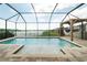 Inviting screened-in pool area with a hammock, brick pool deck, and lake view, creating a relaxing outdoor oasis at 3091 King Fern Dr, Wimauma, FL 33598