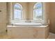 This bathroom features a soaking tub on a platform, two windows, and white tiling with two columns at 3236 Gulf Winds Cir, Hernando Beach, FL 34607