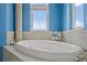 Elegant bathroom featuring a luxurious soaking tub with travertine surround and natural light at 3236 Gulf Winds Cir, Hernando Beach, FL 34607