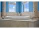 Corner tub with windows in luxury bath featuring architectural columns and tile surround at 3236 Gulf Winds Cir, Hernando Beach, FL 34607