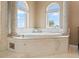 Inviting soaking tub with classic column accents and arched windows providing natural light at 3236 Gulf Winds Cir, Hernando Beach, FL 34607