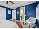 Bright bedroom featuring blue walls, tray ceiling, and a comfortable sitting area with natural light at 3236 Gulf Winds Cir, Hernando Beach, FL 34607