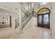 Elegant foyer featuring a grand staircase, travertine flooring, and an ornate wrought iron door at 3236 Gulf Winds Cir, Hernando Beach, FL 34607