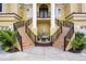 Grand front entrance showcasing dual staircases, and lush landscaping, creating a welcoming approach to the luxury home at 3236 Gulf Winds Cir, Hernando Beach, FL 34607