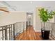 Upper hallway with hardwood floors, wrought iron railing, and large green plant on the glass table at 3236 Gulf Winds Cir, Hernando Beach, FL 34607