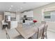 Open kitchen and dining room with light wood table and seating for six at 33700 Hamilton Hill Ln, Wesley Chapel, FL 33545