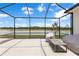 Screened lanai with view of the lake beyond and lounge furniture at 33700 Hamilton Hill Ln, Wesley Chapel, FL 33545