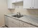 Clean kitchen featuring white cabinetry, stainless steel sink, and marble-look countertops at 3455 Countryside Blvd # 33, Clearwater, FL 33761