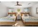 Bright bedroom featuring two beds, ceiling fan, and a decorative palm tree art print for a serene ambiance at 3691 Center Cir, Largo, FL 33774