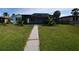 Backyard view highlighting a walkway, screened lanai, and lush green lawn at 3839 Star Island Dr, Holiday, FL 34691