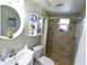 Updated bathroom features a large round mirror, tiled shower, and neutral decor at 3839 Star Island Dr, Holiday, FL 34691