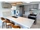Modern kitchen with gray cabinets, island with seating, and stainless steel appliances at 3839 Star Island Dr, Holiday, FL 34691