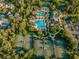 Aerial view of tennis courts and a pool with sun umbrellas, palm trees and parking at 3922 Silverlake Way, Wesley Chapel, FL 33544