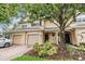 Inviting townhome boasts a brick driveway, attached garage, and a well-maintained lawn with lush landscaping at 3922 Silverlake Way, Wesley Chapel, FL 33544