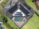 Birds eye view of a home with solar panels and a screened pool enclosure, showcasing the backyard and patio at 4049 Wellington Pkwy, Palm Harbor, FL 34685