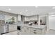 This is a spacious kitchen featuring white cabinets, a tile backsplash, granite counters and stainless appliances at 4049 Wellington Pkwy, Palm Harbor, FL 34685