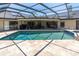 Spacious screened-in pool with travertine deck and comfortable seating area at 4049 Wellington Pkwy, Palm Harbor, FL 34685