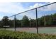 Well-maintained tennis court surrounded by a secure fence and lush greenery, offering a private playing experience at 4049 Wellington Pkwy, Palm Harbor, FL 34685