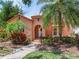 Quaint peach stucco home with a red tile roof, arched doorway, and lush tropical landscaping at 4521 W Azeele St, Tampa, FL 33609
