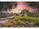 This backyard view shows the home with a shed and mature trees under a pink-hued sunset at 4684 72 N Ave, Pinellas Park, FL 33781