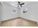 This is a bedroom with light wood floors, fan, and two windows at 4684 72 N Ave, Pinellas Park, FL 33781